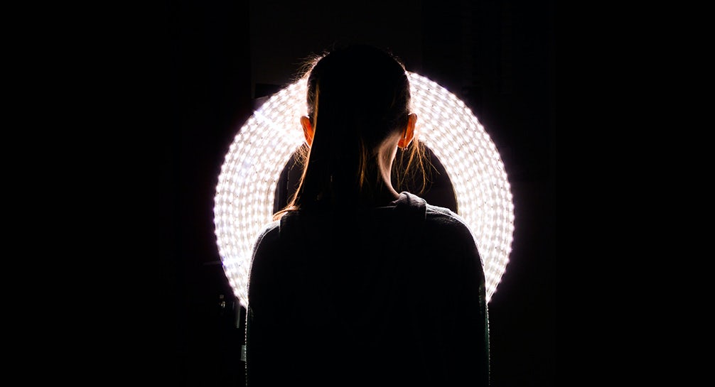 A woman's head is lit up by a circular light.