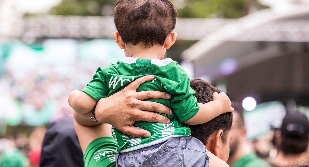 A man holds a child in his arms at a soccer game.