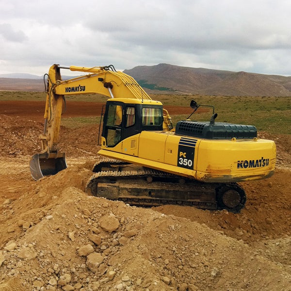 A yellow excavator in a dirt field.