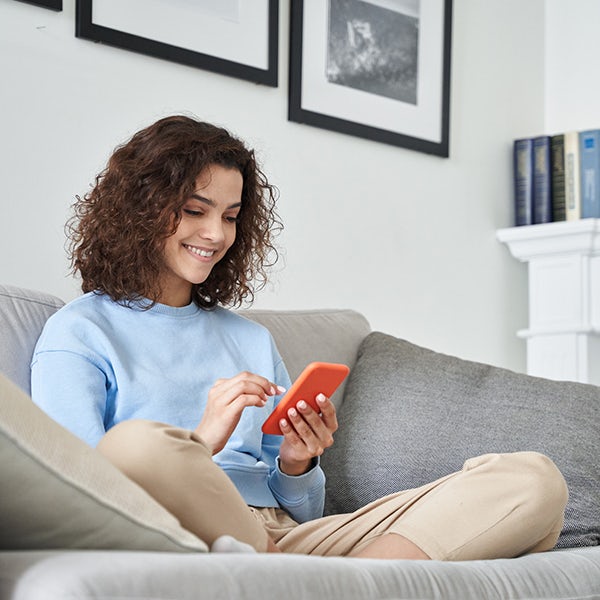 A woman sitting on a couch looking at her phone.