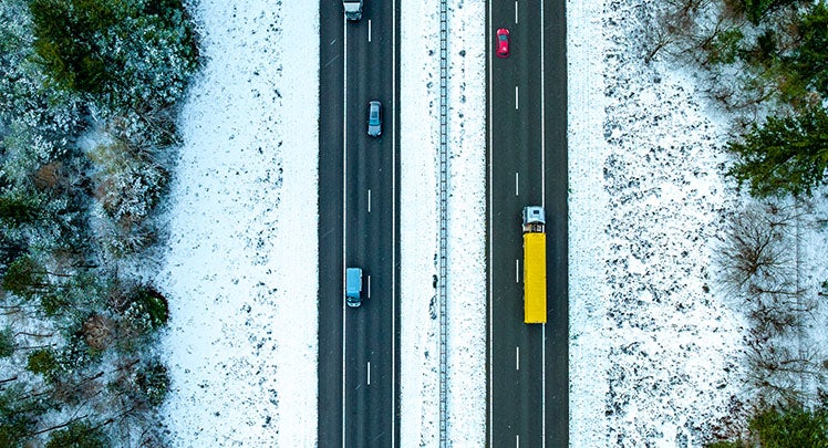 An aerial view of a snowy road with cars on it.