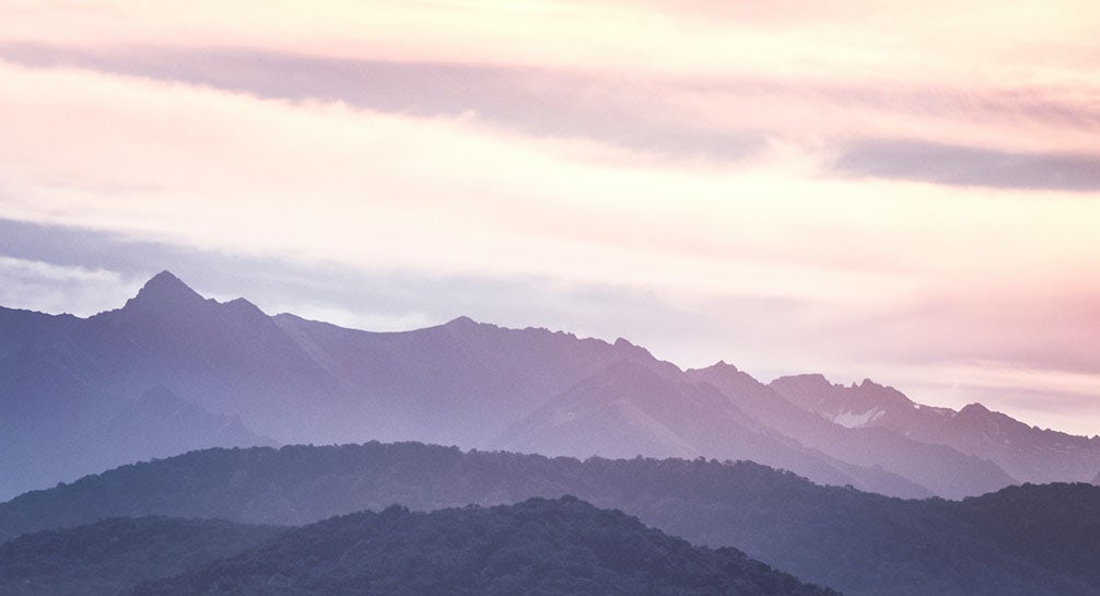 A mountain range with a pink sky in the background.