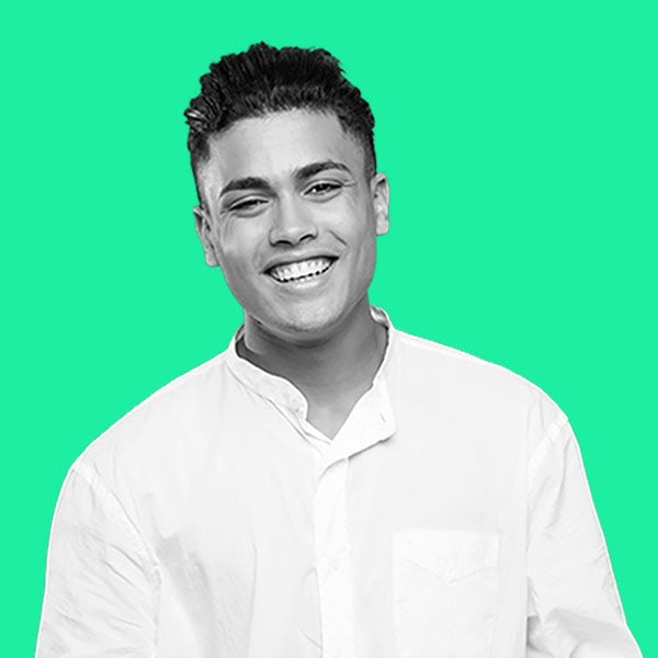 A man in a white shirt smiling against a green background.