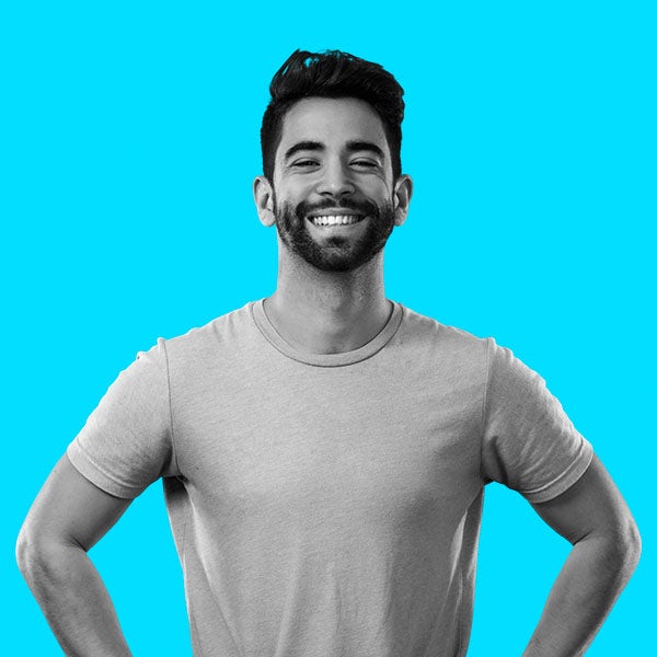 A smiling man with a beard standing on a blue background.