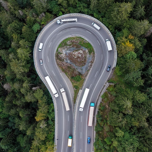 An aerial view of a curved highway in the forest.