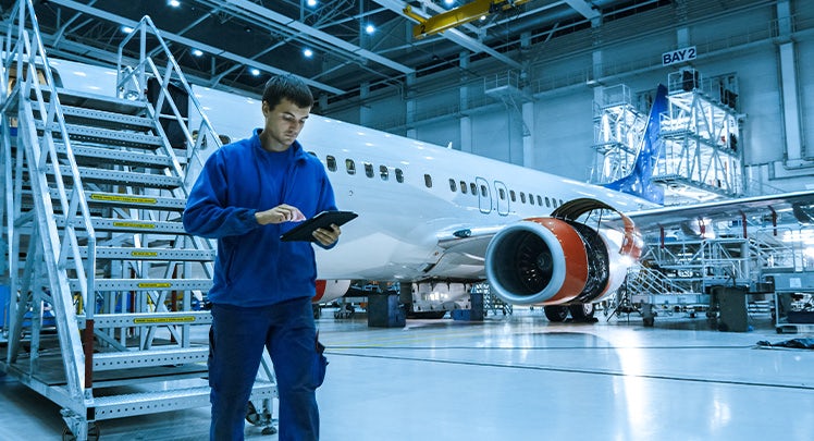 A man is standing next to an airplane in a factory.