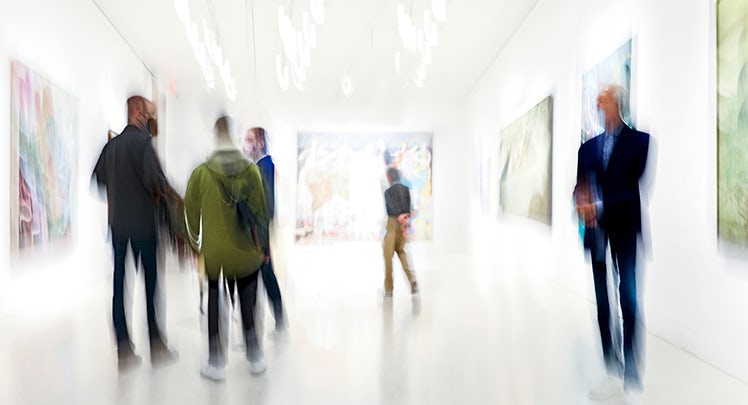 A group of people walking through an art gallery.