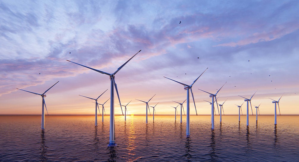 Wind turbines in the ocean at sunset.