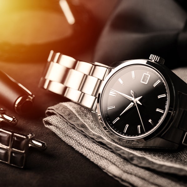 A black watch and cufflinks on a black cloth.