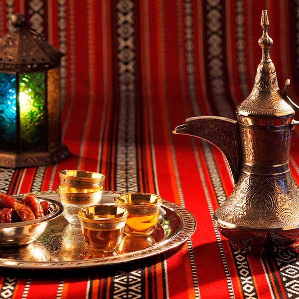 A silver teapot on a table next to a striped tablecloth.