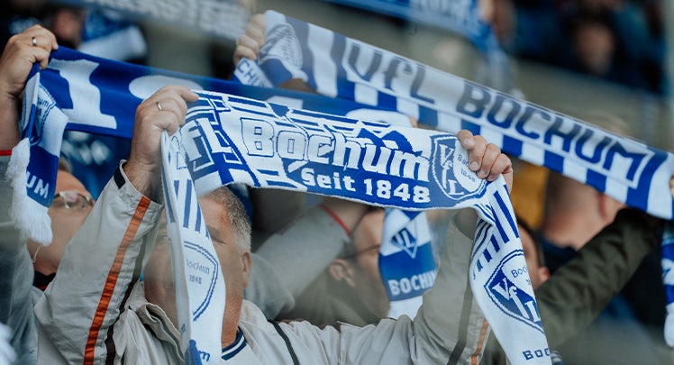 A group of people holding up a blue and white scarf.