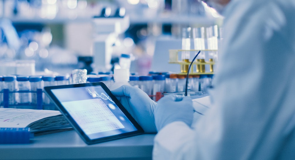 A scientist is using a tablet in a lab.