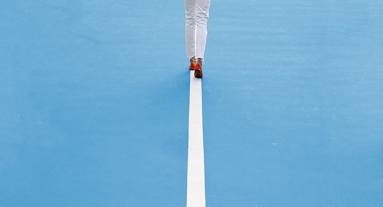 A woman walking on a tennis court with a tennis racket.