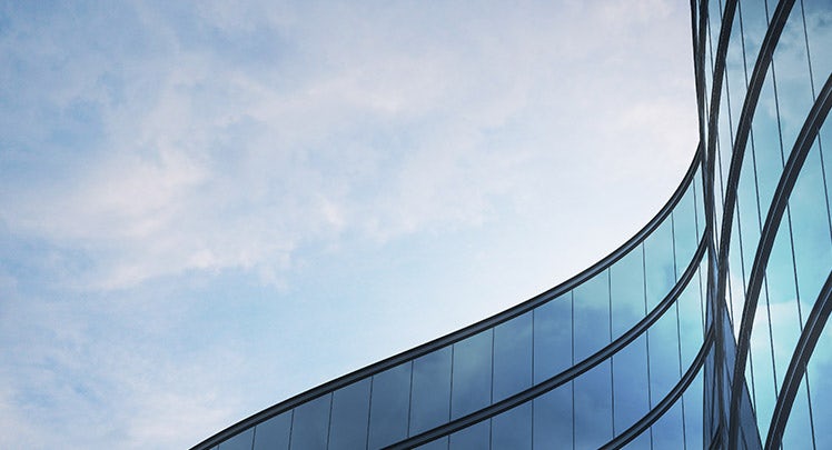 An image of a glass building with a blue sky.