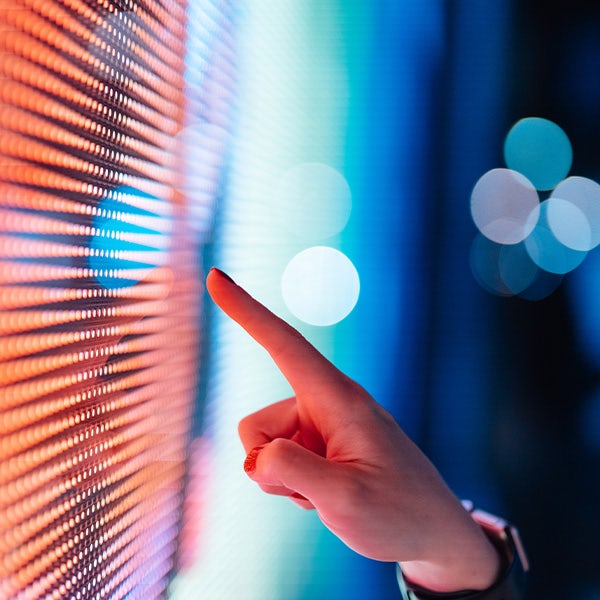 A person pointing at a screen with colorful lights.