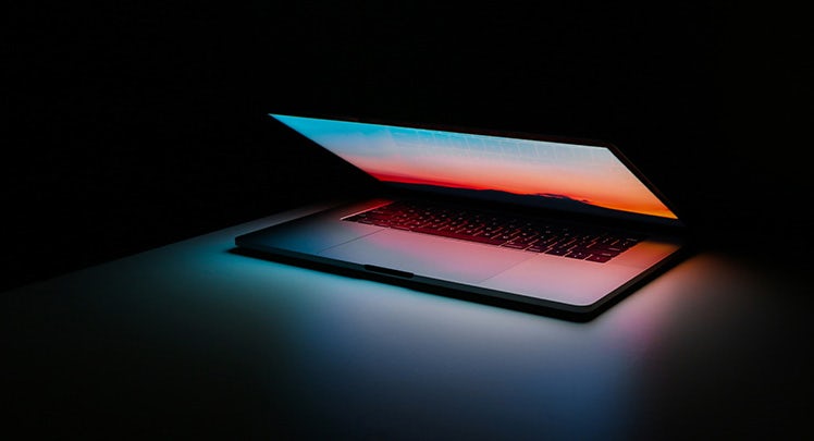 A laptop is lit up in the dark.