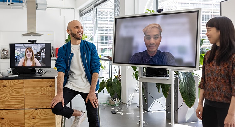 A group of people in an office talking on a video conference.