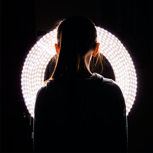 A girl's head in front of a circular light.