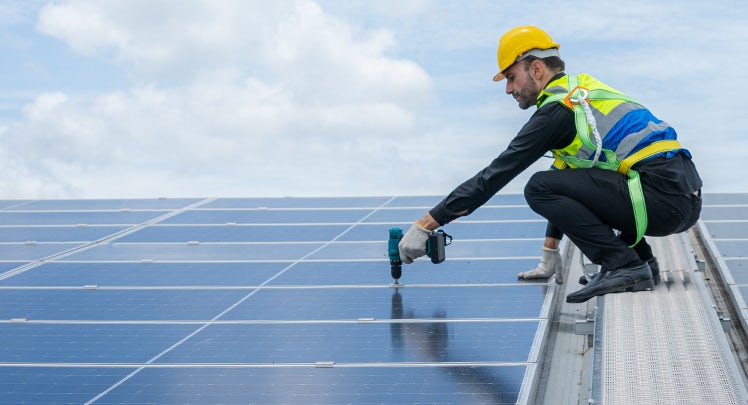 A man working on a solar panel on a roof.