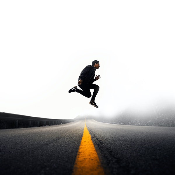 A man is jumping in the air on a foggy road.