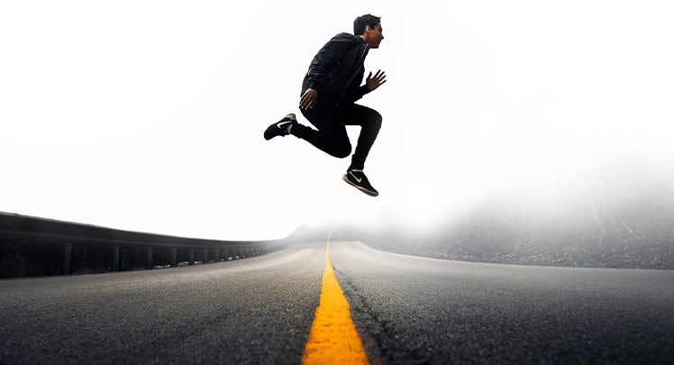 A man jumping in the air on a road.