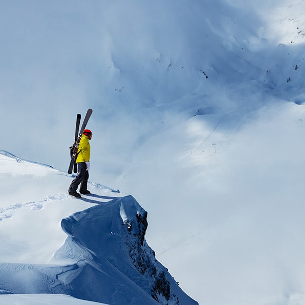 A person standing on top of a mountain holding skis.