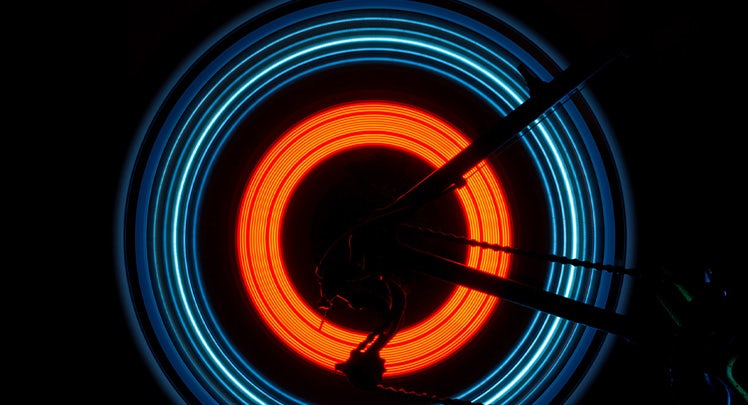 A close up of a bicycle wheel with neon lights.