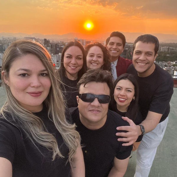 A group of people posing for a selfie at sunset.