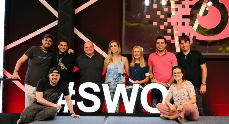 A group of people posing in front of a sign that says swo.