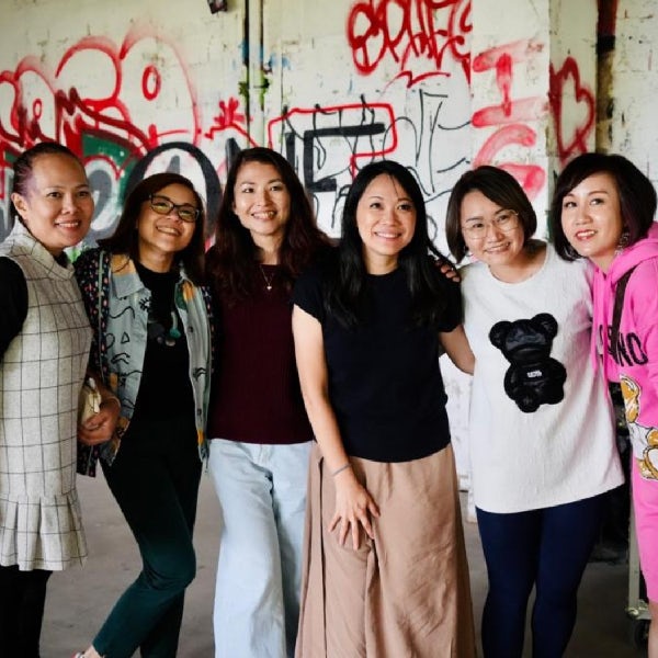 A group of women standing in front of graffiti covered walls.