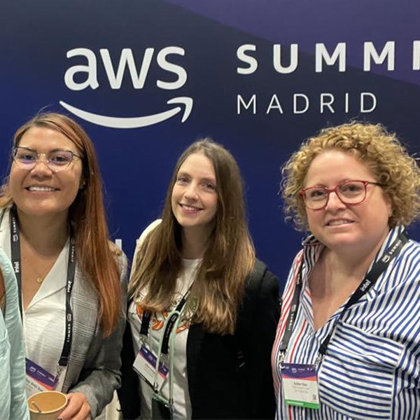 Three women standing in front of aws summit madrid.