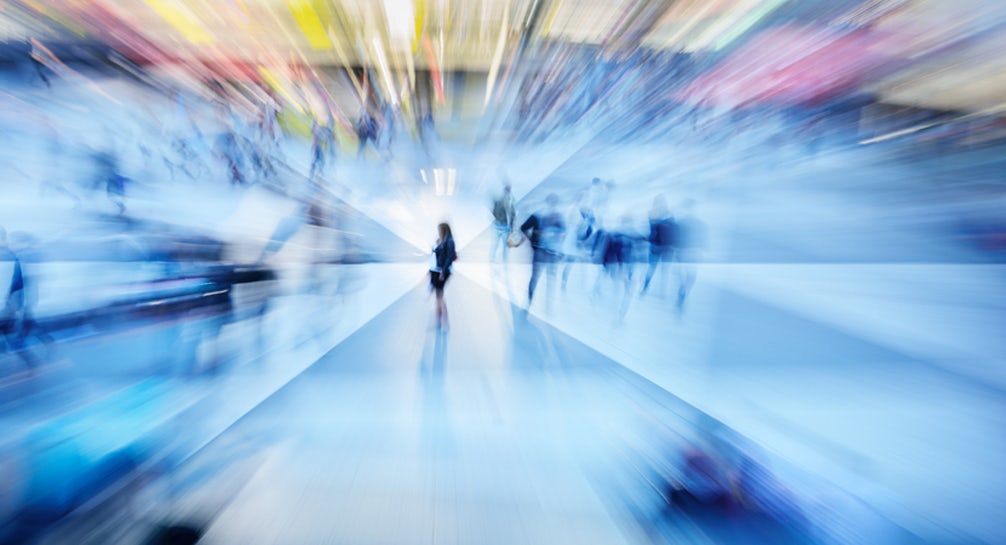 A blurry image of people walking in a shopping mall.