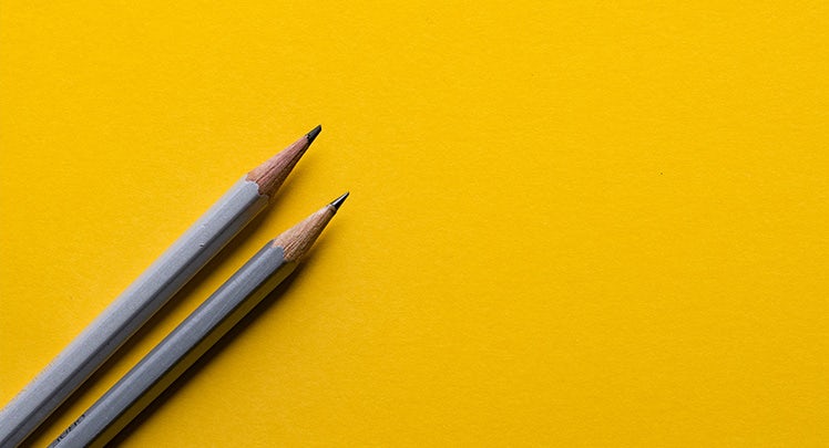 Two pencils on a yellow background.