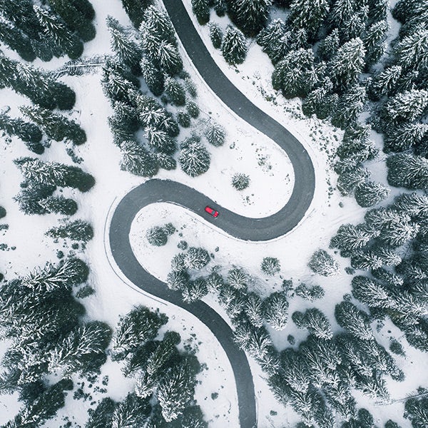 A car driving on a winding road surrounded by snow.
