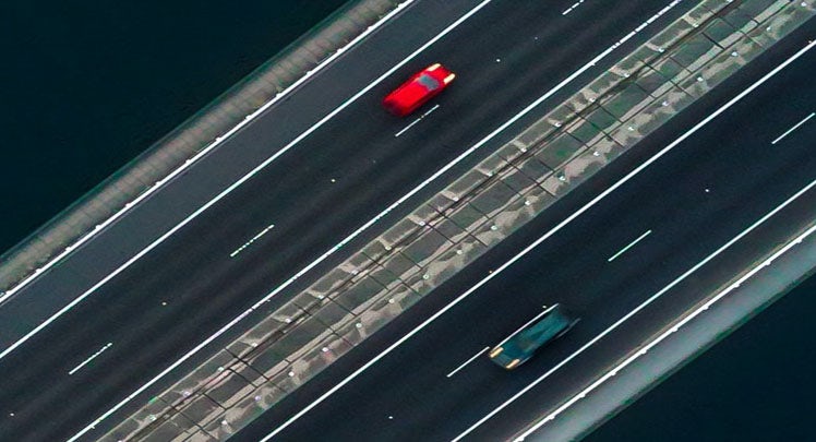 An aerial view of two cars driving on a highway.