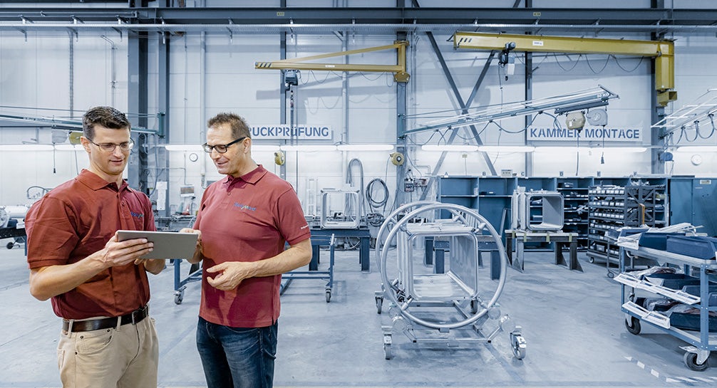 Two men standing in a factory looking at a tablet.