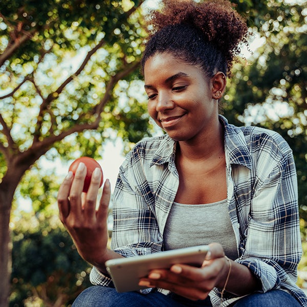 A woman sitting on the ground holding an apple.