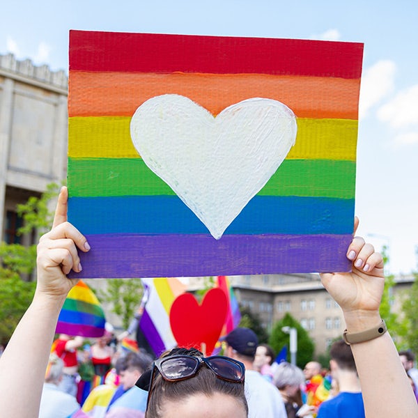 A woman holding up a rainbow colored heart.