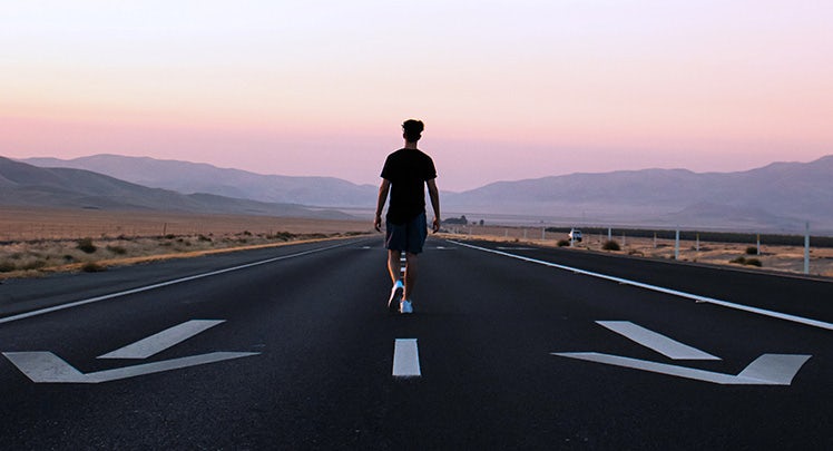 A man is walking down an empty road.