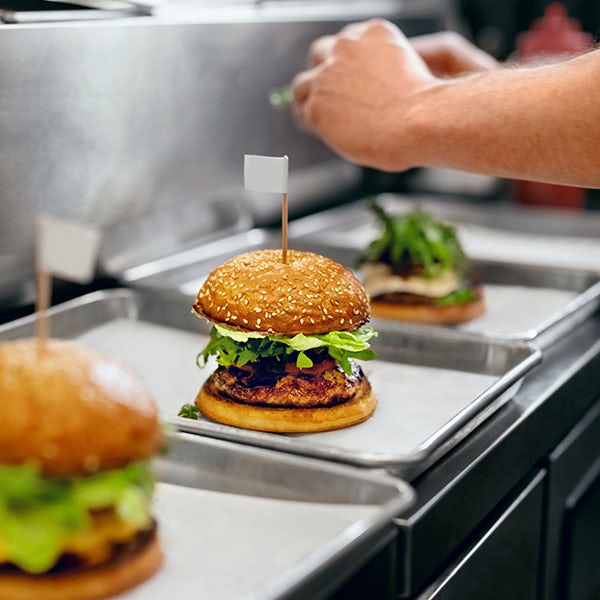 A person is putting burgers on trays.