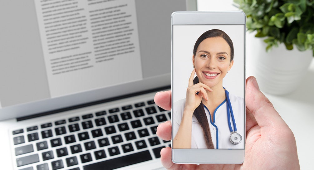 A woman is holding up a smartphone with a doctor's face on it.
