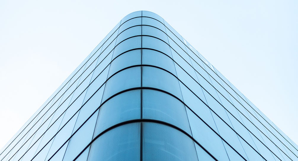 An image of a glass building against a blue sky.