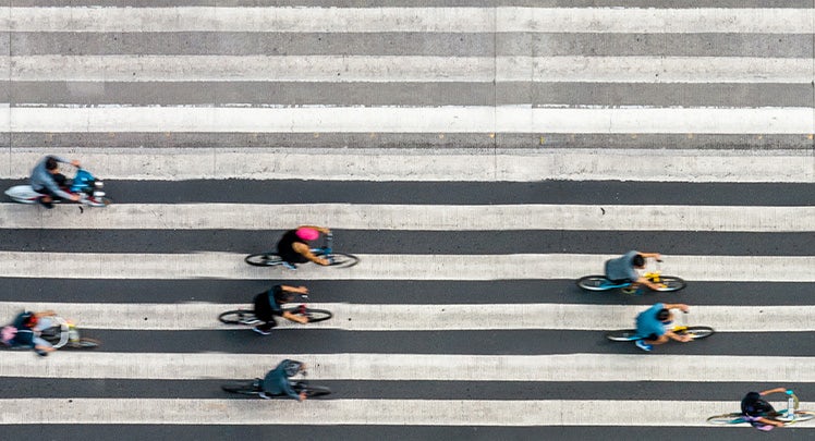 A group of people riding bicycles in a crosswalk.