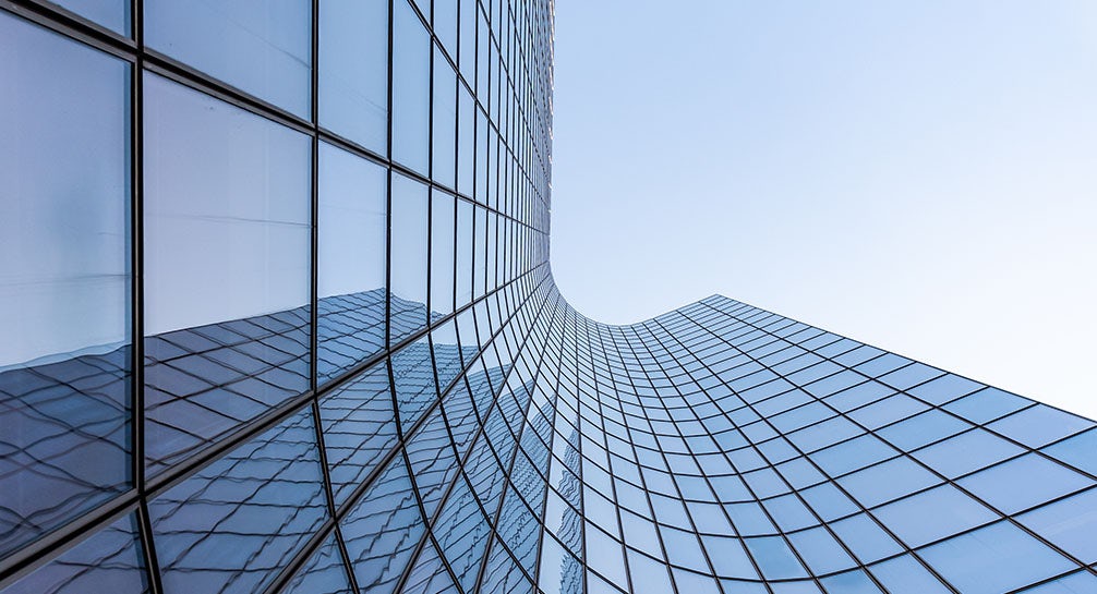 A view of a glass building with blue sky in the background.