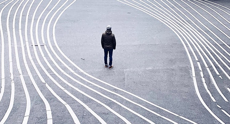 A person standing in the middle of a street with white lines.