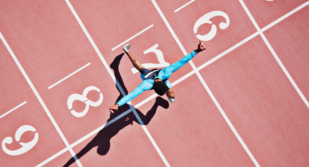 A woman running on a track with her arms outstretched.