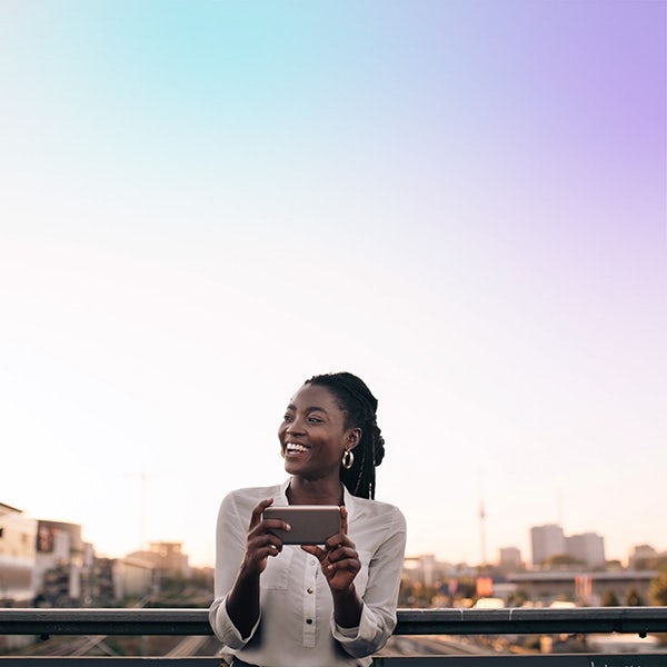 Young african american woman looking at her phone on a balcony.