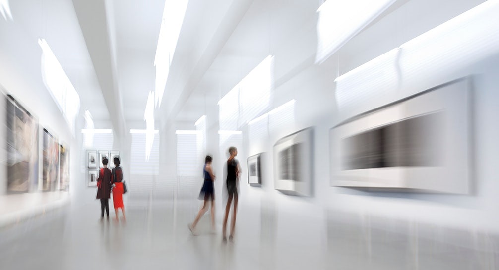 A blurry image of people walking through an art gallery.