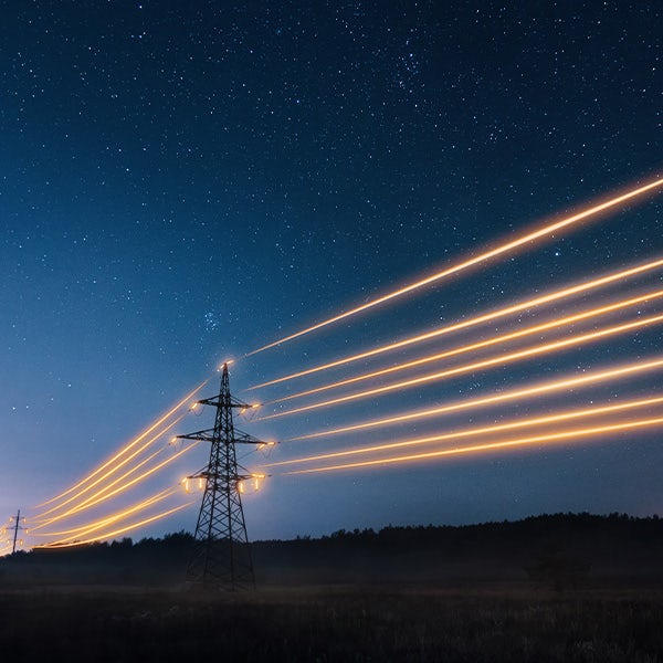 An image of an electricity pylon at night with a starry sky.
