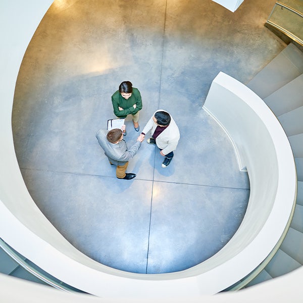 Three people standing at the top of a spiral staircase.
